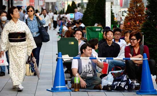 Một người phụ nữ mặc kimono đi ngang qua khu vực xếp hàng trước cửa một Apple Store khác tại Nhật Bản. Không khí ngày bán iPhone 5S, iPhone 5C đầu tiên trên thế giới