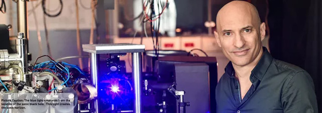 Ánh sáng xanh phát ra từ địa điểm của hố đen nhân tạo, chính ánh sáng ấy tạo nên đường chân trời của hố đen.  Ánh sáng xanh phát ra từ địa điểm của hố đen nhân tạo, chính ánh sáng ấy tạo nên đường chân trời của hố đen.