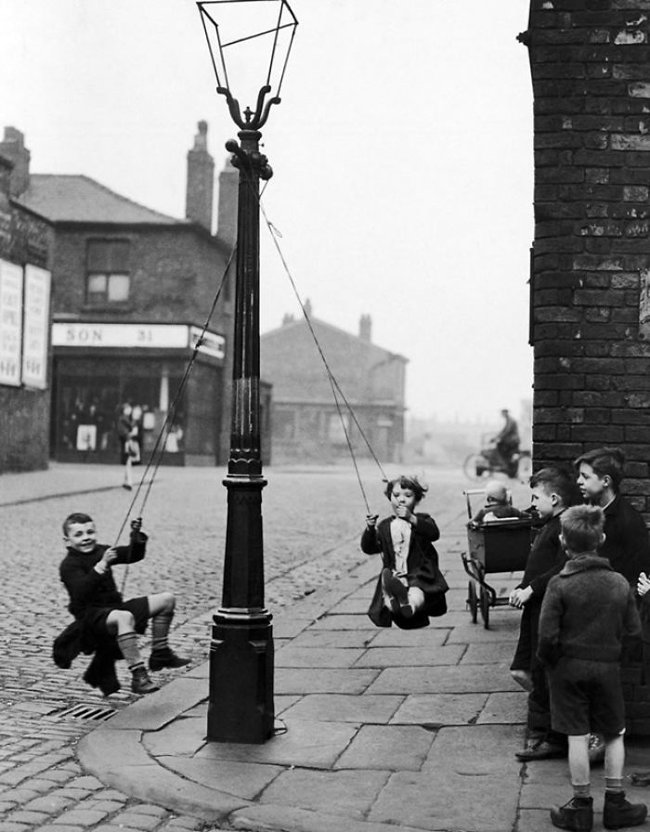 Những đứa trẻ ở Manchester đang nô đùa trên những chiếc xích đu treo lên cột đèn ven đường năm 1946
