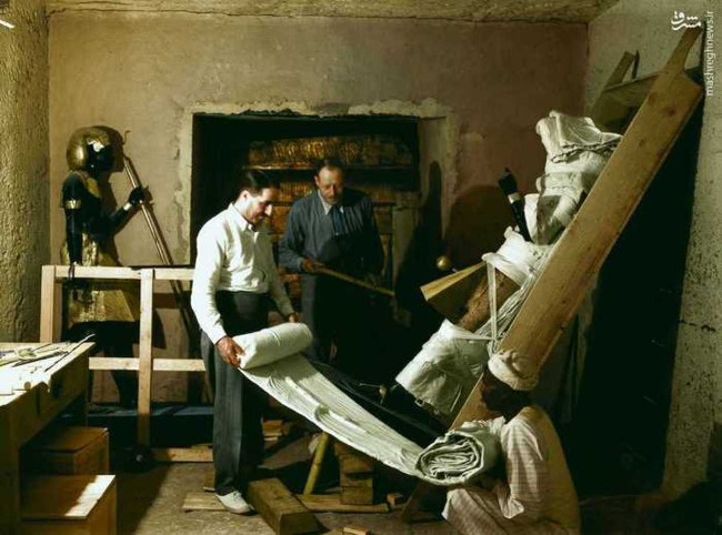 Howard Carter, Arthur Callender và một công nhân Ai Cập dùng vải quấn một bức tượng lính canh để chuẩn bị di dời