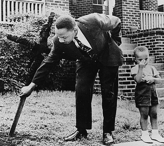 Mục sư Martin Luther King, nhà hoạt động nhân quyền chống phân biệt chủng tộc nổi tiếng, đứng cạnh con trai và gỡ bỏ cây thánh giá bị đốt ở sân trước nhà năm 1960