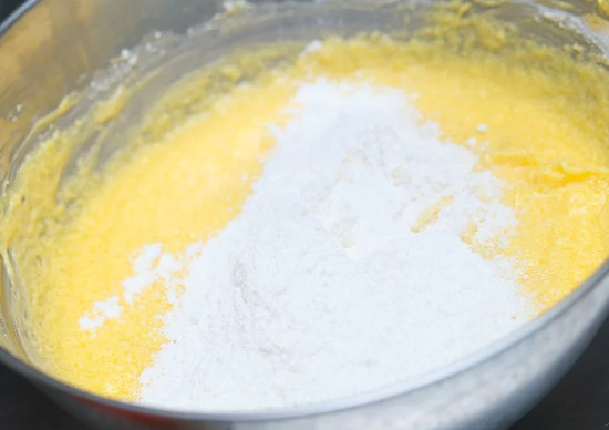 Cho hỗn hợp bột mỳ và bột nở vào theo từng lượng nhỏ rồi trộn đều