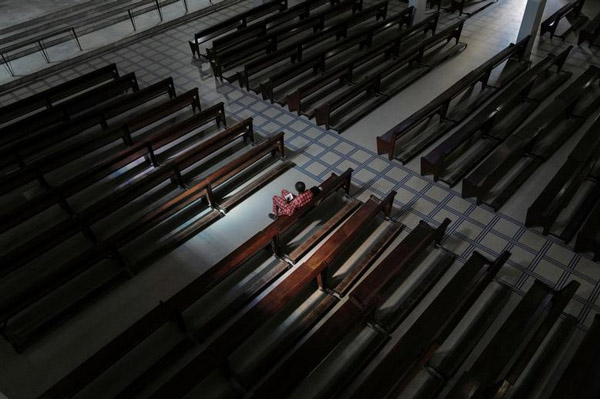 Một tín hữu ngồi một mình trong thánh lễ chủ nhật tại Nhà thờ Notre-Dame des Victoires