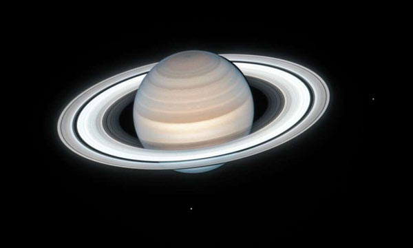 Bức ảnh chân dung mới của sao Thổ do kính viễn vọng Hubble chụp. Bức ảnh này có màu sắc đậm nét hơn do sương mù đỏ lan khắp Bắc bán cầu của hành tinh vào mùa xuân và mùa hè. Trong bức ảnh còn xuất hiện 2 hai mặt trăng của nó là Enceladus và Mimas. Ảnh: NASA/ESA.