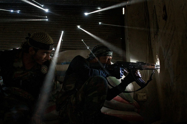 Hai binh sĩ quân nổi dậy Syria căng thẳng bảo vệ vị trí của họ trong khu phố Karmel Jabl. Bức tường phía sau họ cũng đã bị đạn xuyên thủng  nhiều lỗ.