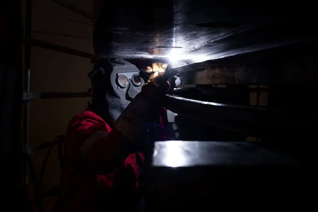 Một kỹ thuật viên đang thực hiện mối hàn trên tấm chắn bên ngoài của buồng siêu lạnh.