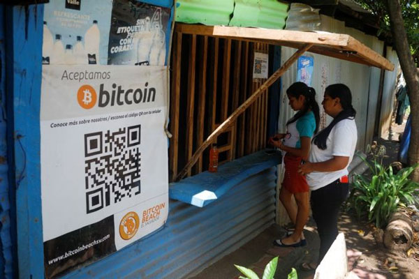 Áp phích quảng cáo Bitcoin bên ngoài một quầy tạp hóa vào hồi tháng 6/2021. Ảnh: Reuters.