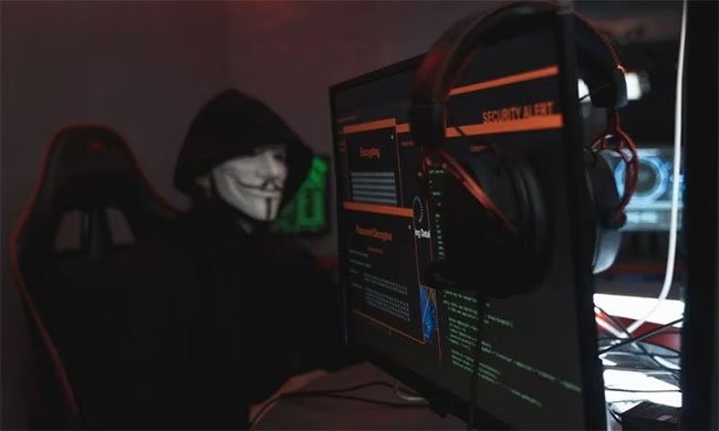 Người mặc trang phục ẩn danh trên máy tính với cảnh báo an ninh