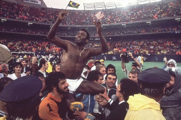 Pelé được mọi người công kênh khi cầm trên tay cờ của Mỹ và Brazil vào năm 1977. Ông vừa tham gia trận đấu cuối cùng của mình giữa Cosmos và Santos. Pelé chơi cho mỗi đội mỗi hiệp.