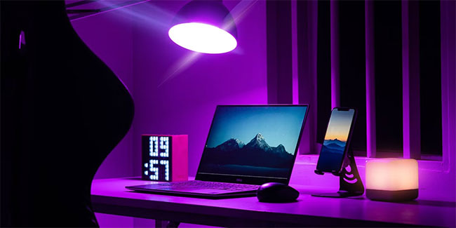 Laptop bên cạnh chuột, điện thoại, đồng hồ, được thắp sáng bằng ánh sáng màu tím