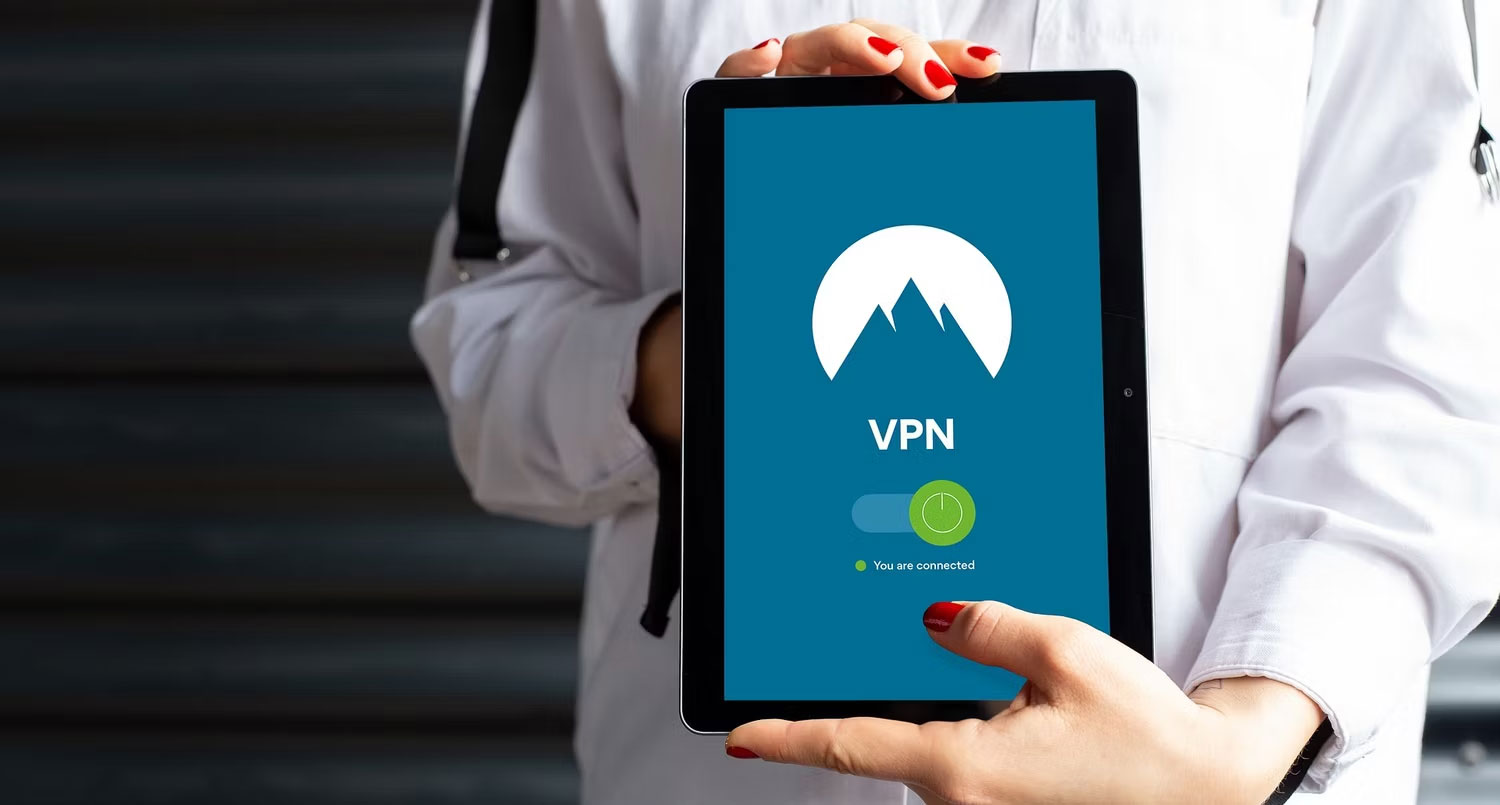Người cầm máy tính bảng có ứng dụng VPN đang hoạt động trên màn hình