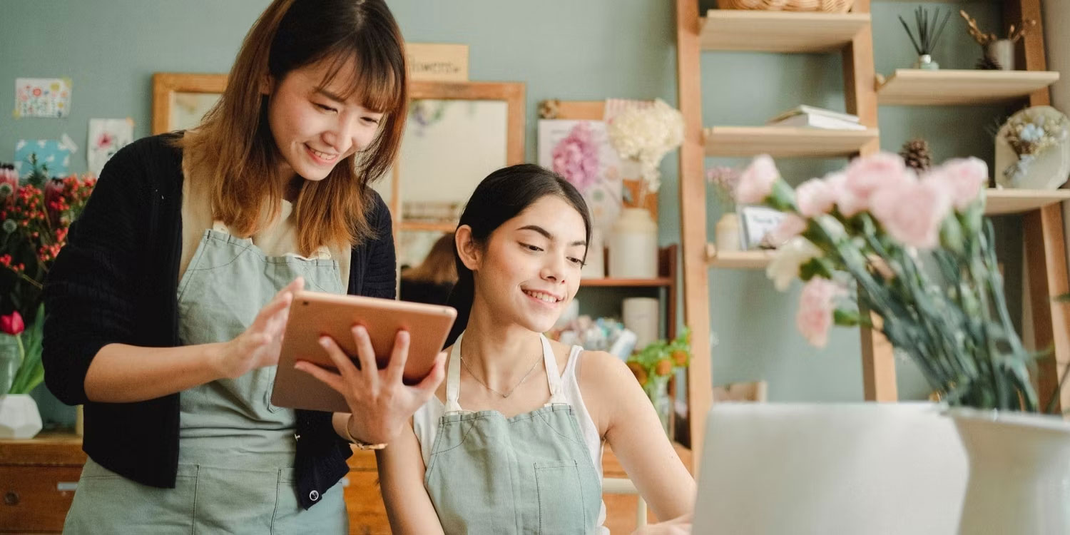 Hai người phụ nữ đang nhìn vào máy tính và iPad