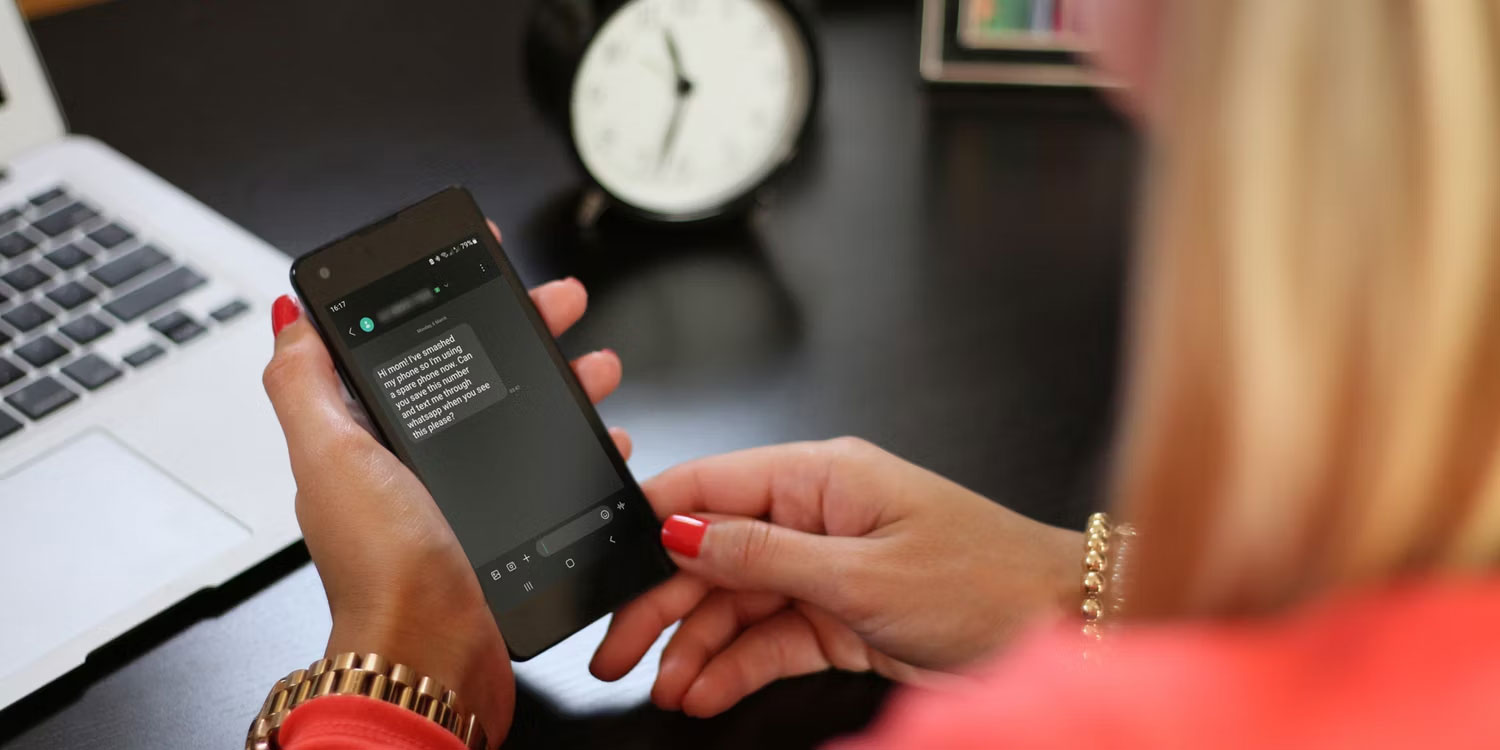 Người phụ nữ cầm điện thoại Android với tin nhắn Phishing