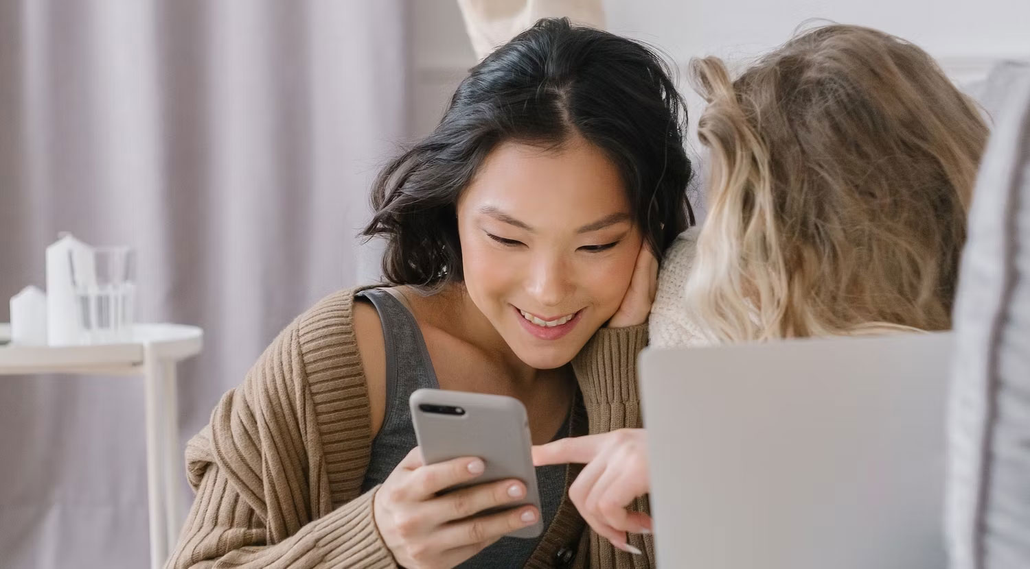 Hai người phụ nữ nhìn vào điện thoại thông minh