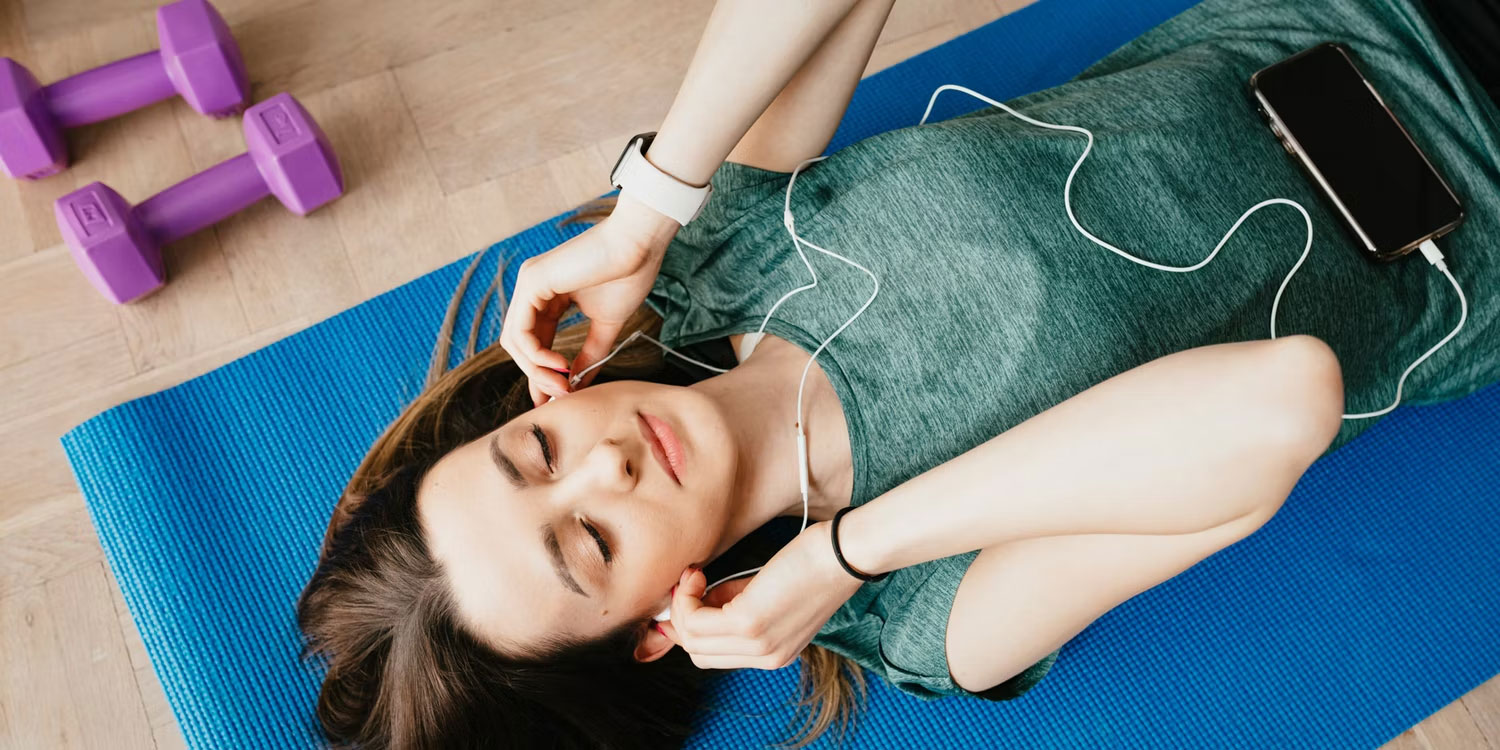 Người phụ nữ nằm trên thảm tập nghe nhạc
