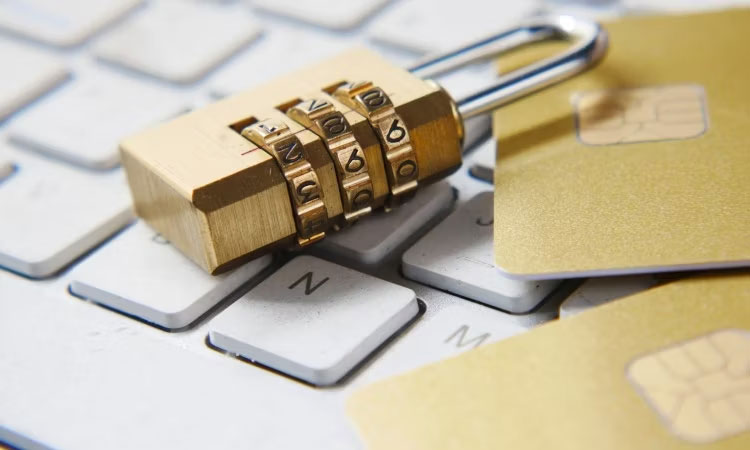 Một ổ khóa vàng và hai thẻ tín dụng vàng nằm trên bàn phím.