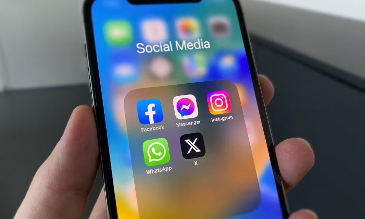 Một người cầm chiếc iPhone màu đen hiển thị các biểu tượng mạng xã hội cho Facebook, Messenger, Instagram, WhatsApp và Twitter.