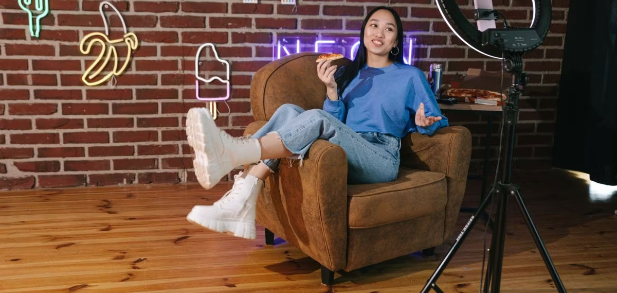 Cô gái ngồi trên ghế trước ống kính ăn pizza