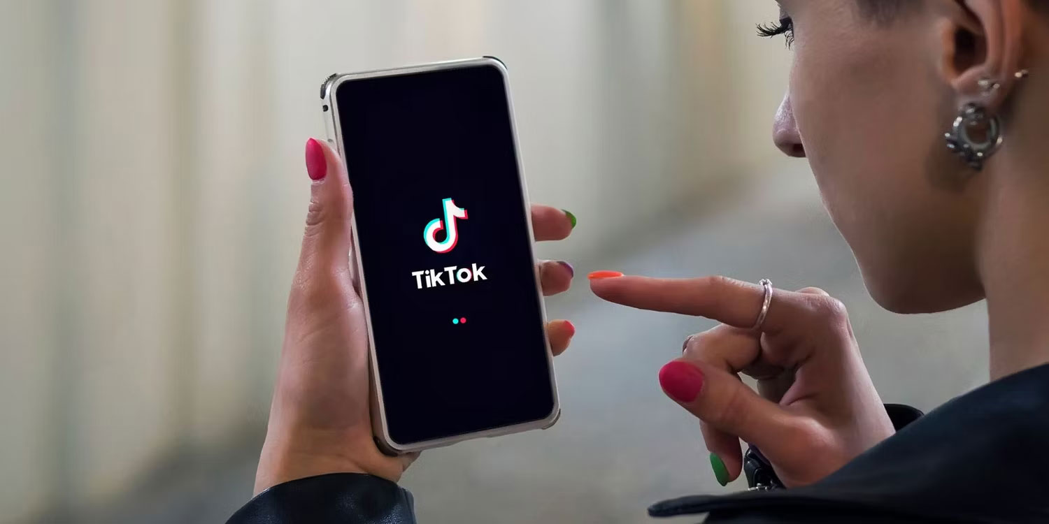 Người phụ nữ cầm điện thoại có logo TikTok trên màn hình