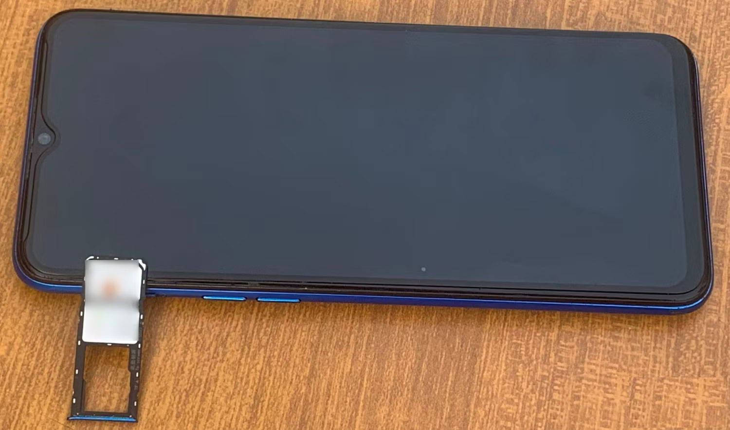 Một chiếc điện thoại Android trên bàn với khay SIM bên cạnh