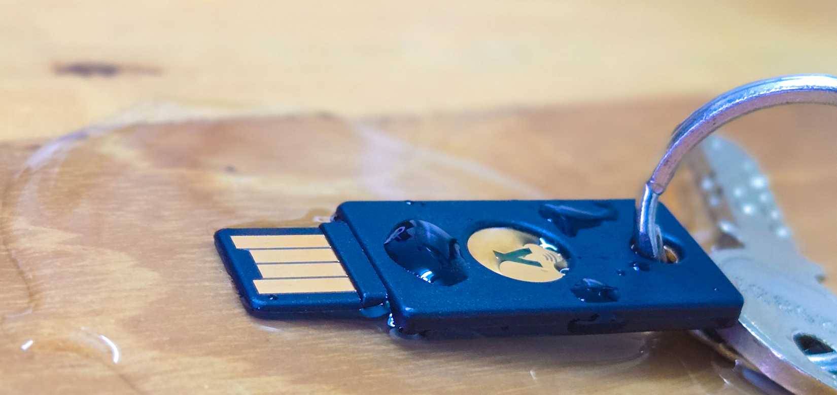 YubiKey bị ngập trong nước đổ trên bàn gỗ