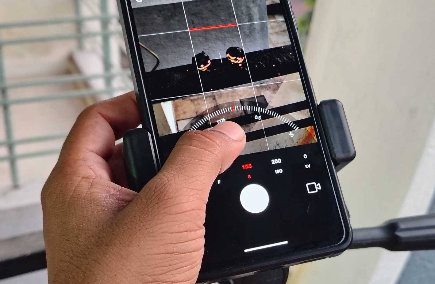 Điều chỉnh tốc độ màn trập bằng ngón tay cái trên smartphone đặt trên giá ba chân