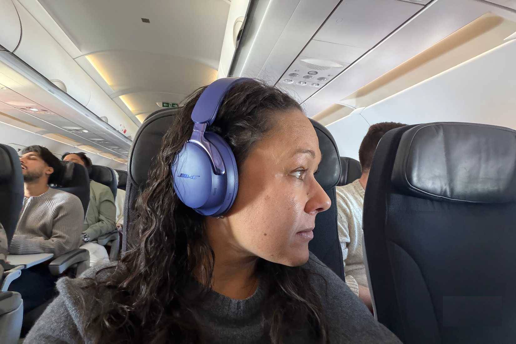 Một phụ nữ đeo tai nghe Bose QuietComfort Ultra 2 trên máy bay